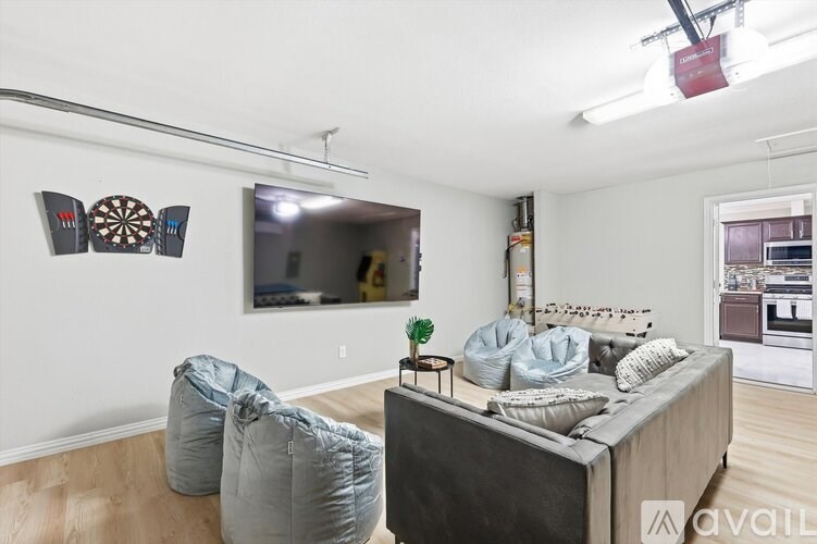 A living room with a grey sofa, two bean bag chairs, and a dartboard on the wall.