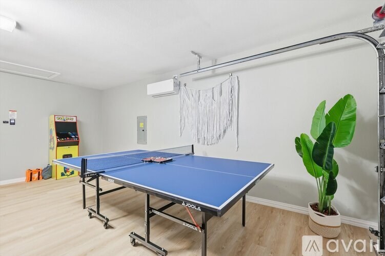 A blue table tennis table is in a room with a plant and a hanging net.