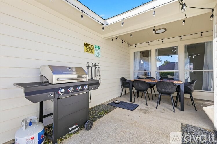 A patio with a grill and chairs.