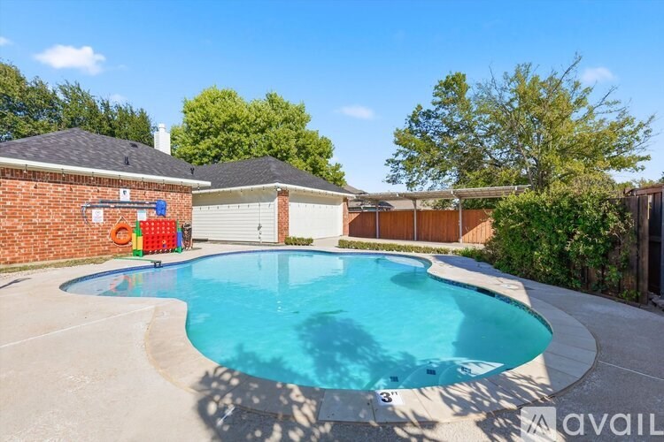 A small residential pool with a concrete patio and a house in the background.