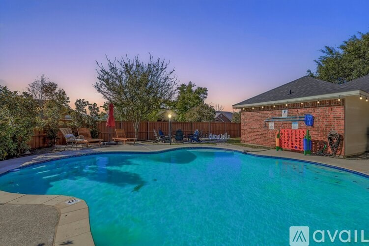 A pool surrounded by a deck and trees at dusk.