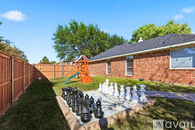 A giant chess set is set up on a lawn in front of a house.