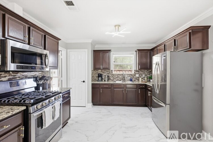 A kitchen with brown cabinets and a marble floor.