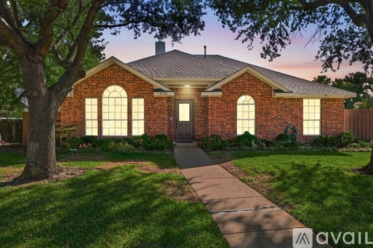 A house with a brick facade and a large tree in front.