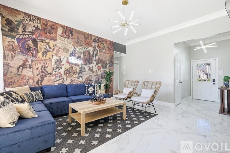A living room with a blue sofa, wooden coffee table, and a wall covered in posters.
