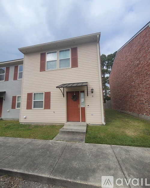 A beige house with a red door and a garage door opener.