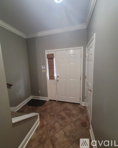 A hallway with a white door and a brown tiled floor.