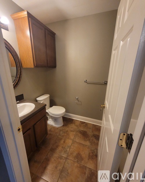 A bathroom with brown cabinets and a white toilet.