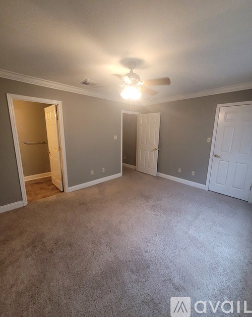 A room with carpeted floor and a ceiling fan.
