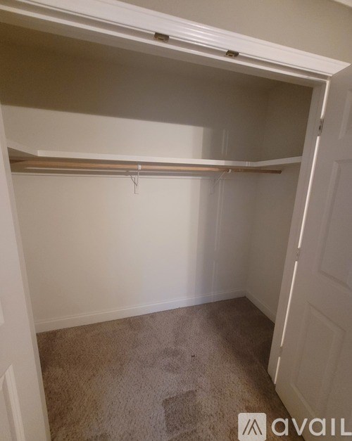 A small, empty room with a carpeted floor and a white door.