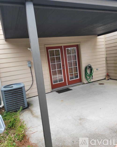 A patio with a door and a wall-mounted air conditioner unit.