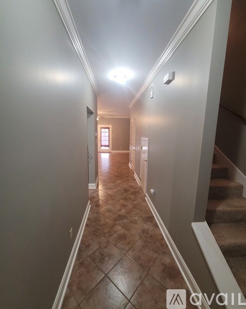 A hallway with a tiled floor and a staircase on the right.