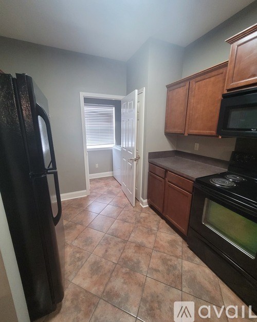 A kitchen with black appliances and brown cabinets.