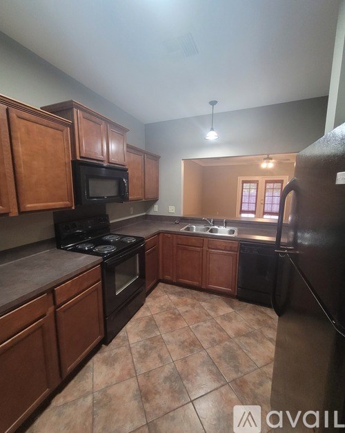 A kitchen with black appliances and brown cabinets.