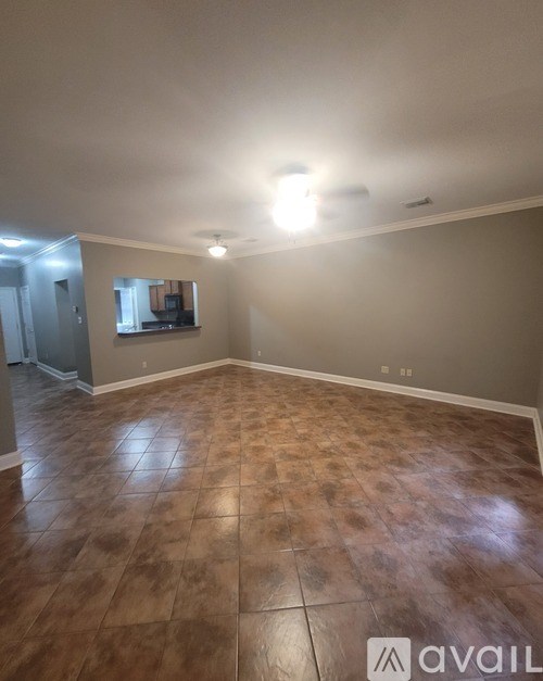 A room with a brown tile floor and a flat screen TV mounted on the wall.
