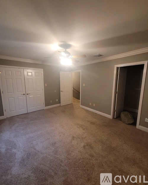 A room with a carpeted floor and a ceiling fan.