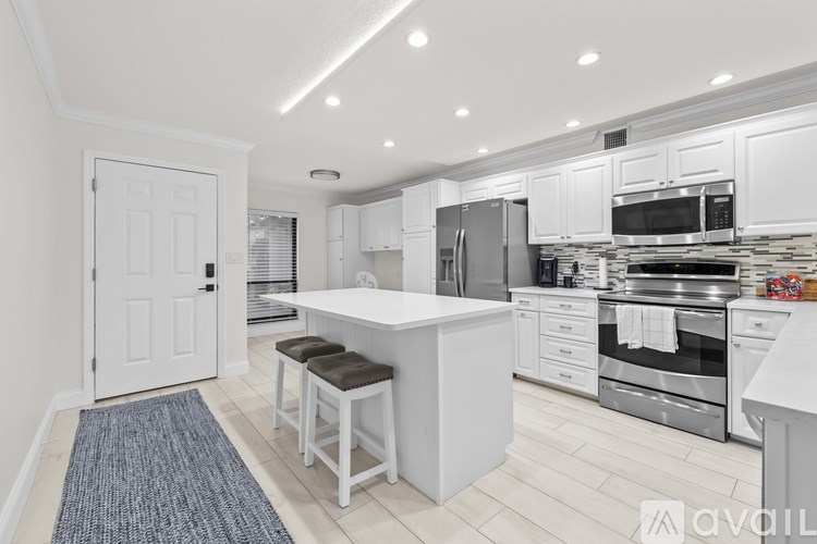 A modern kitchen with white cabinets and stainless steel appliances.
