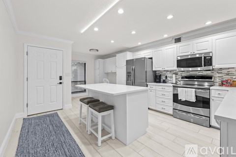 A modern kitchen with white cabinets and stainless steel appliances.
