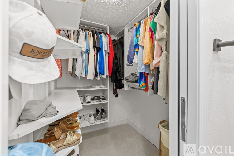 A white closet with clothes and shoes.