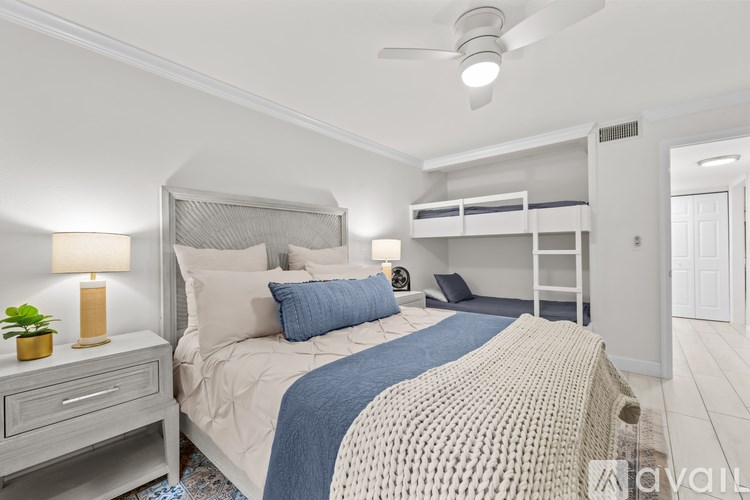 A bedroom with a bed, a nightstand with a lamp, and a ceiling fan.