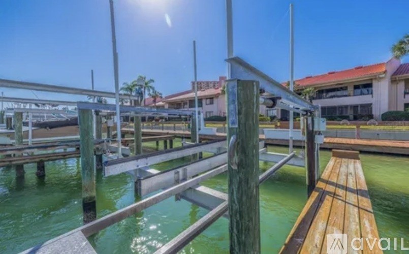 A wooden dock extends into a body of water with a building in the background.