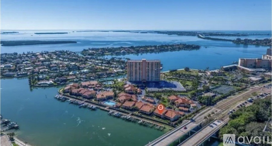 A bird's eye view of a waterfront residential area with a bridge and a tall building.