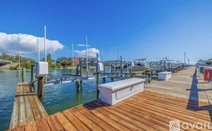 A wooden dock with a white box on it and boats in the background.