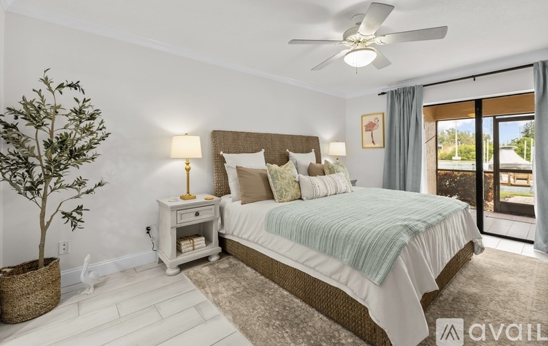 A bedroom with a large bed, a ceiling fan, and a sliding glass door.