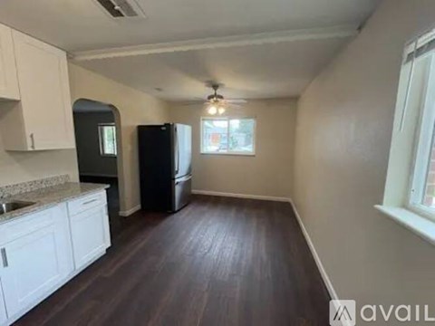 A kitchen with white cabinets and a black fridge.
