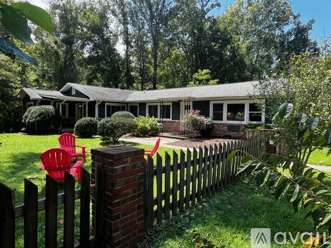A house with a white porch and a red chair in front of it.