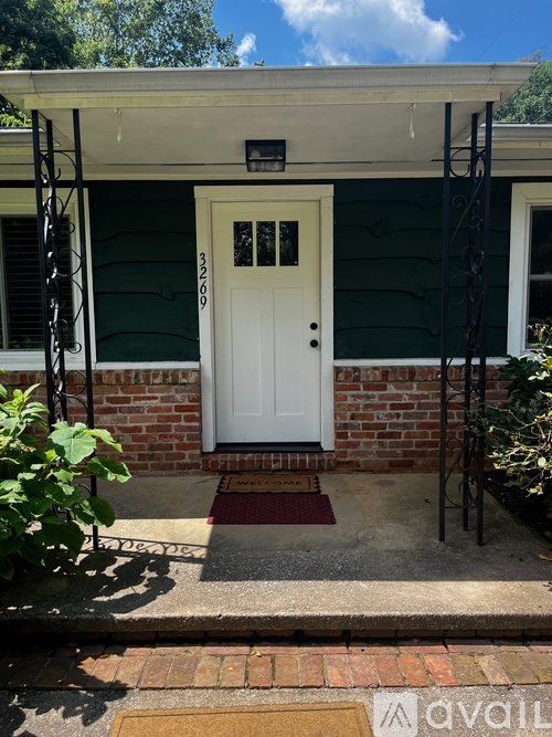 A white door with a black mailbox is on the front of a green house.