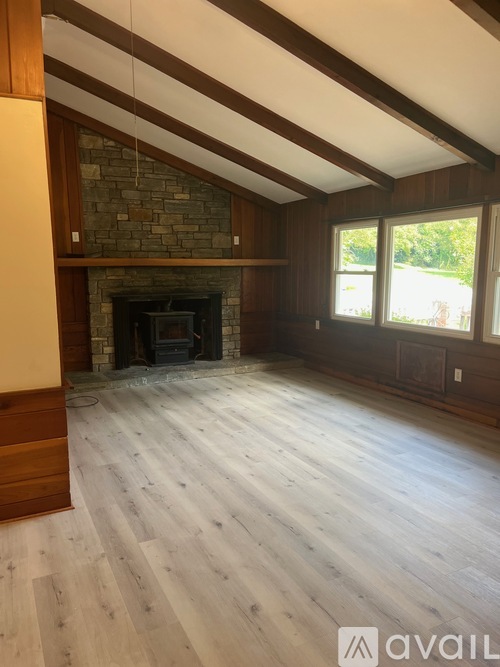 A room with wooden floors and a stone fireplace.