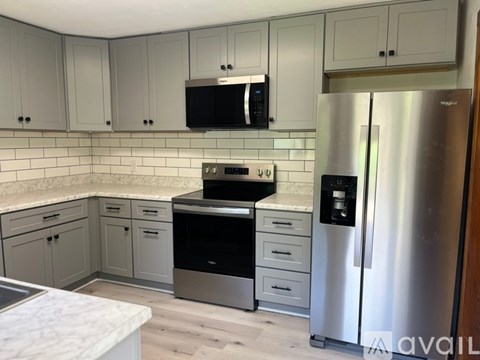 A kitchen with a stainless steel refrigerator and a black microwave above the oven.