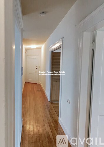 A long hallway with wooden floors and white walls.