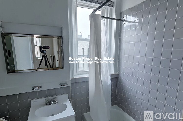 A bathroom with a white sink and grey tiled walls.