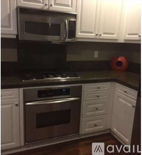 A kitchen with white cabinets and a black countertop.