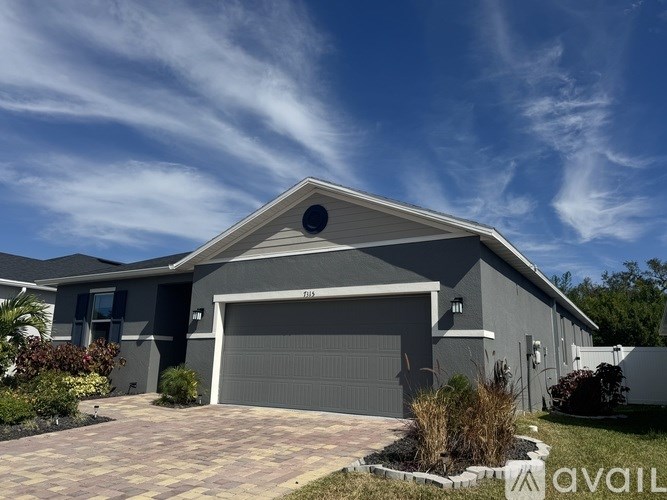 A house with a grey garage door and a driveway made of brick pavers.