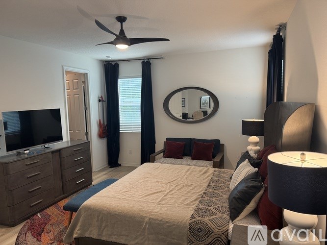 A bedroom with a bed, dresser, and ceiling fan.