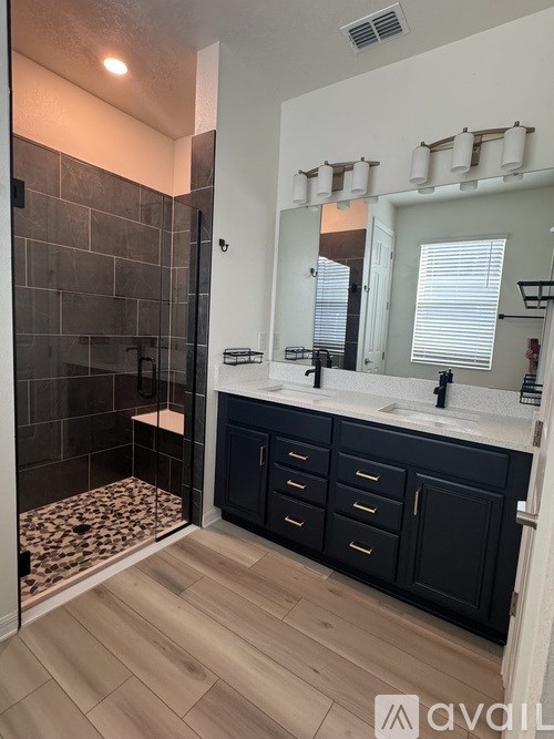 A bathroom with a walk-in shower and double sinks.