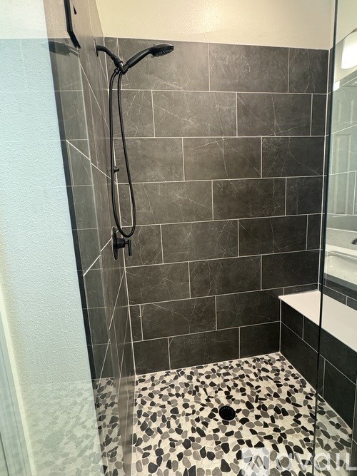 A shower with a black and white tiled floor.