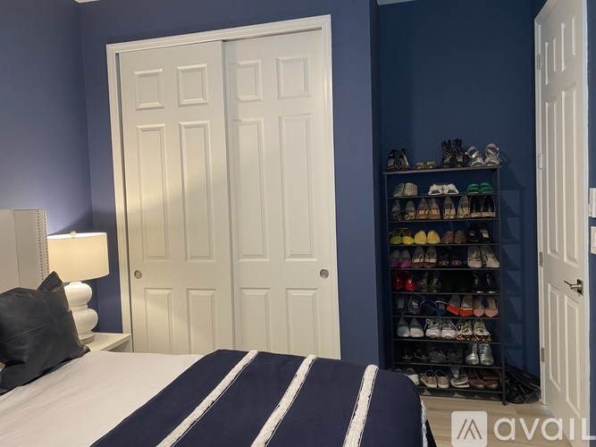 A room with a bed, a shoe rack, and two doors.