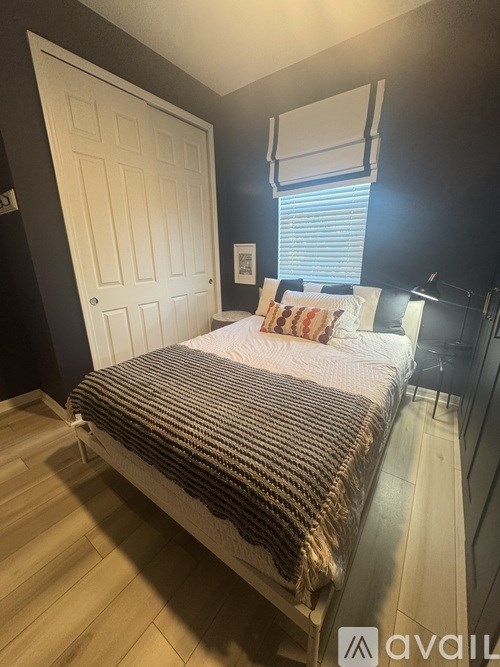 A bedroom with a bed, pillow, and a window with blinds.