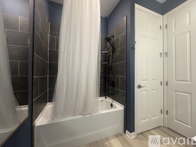 A bathroom with a white tub and shower curtain.
