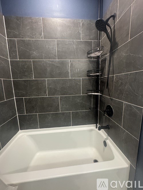 A white bathtub with a shower head and hand held shower.
