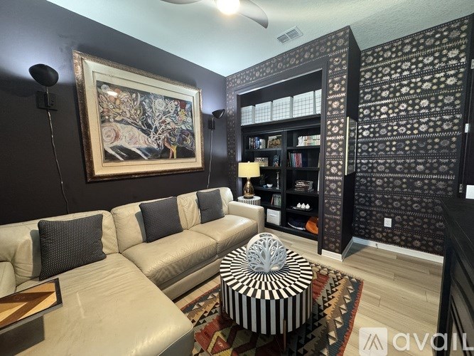 A living room with a white couch and a black and white striped ottoman.