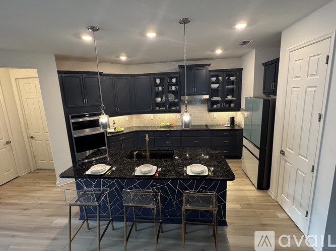 A kitchen with black cabinets and a black island with two chairs.