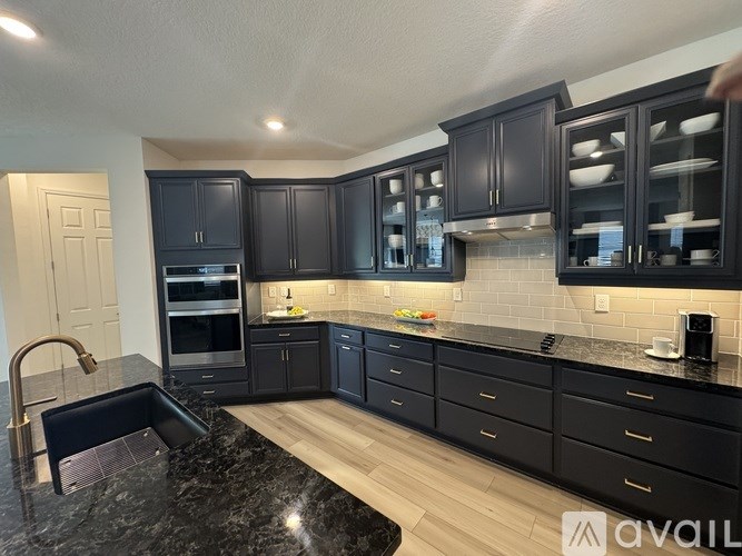 A kitchen with black cabinets and a black marble countertop.