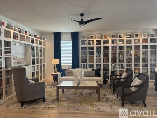 A living room with a grey sofa, a white coffee table, and a ceiling fan.