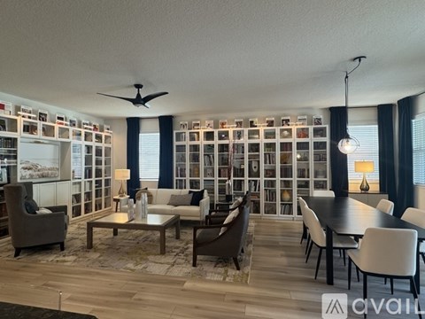 A living room with a dining table and chairs, a sofa, and a ceiling fan.