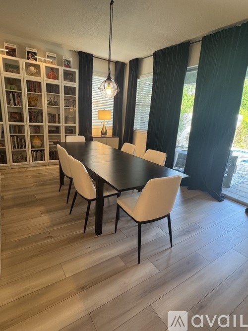A dining room with a black table and white chairs.